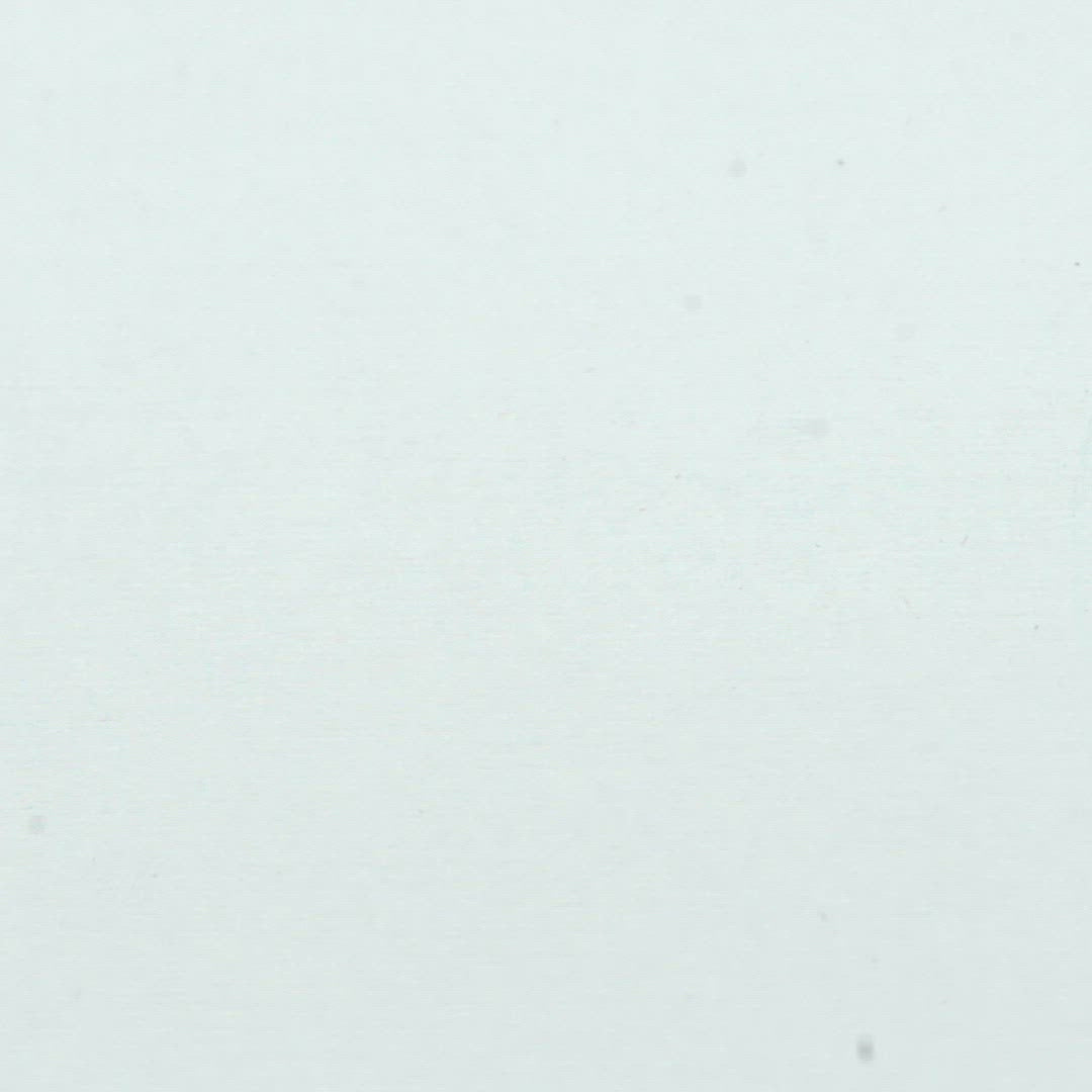 A closeup video of a man stamping on white paper, leaving the line art of a small stylized skull.
