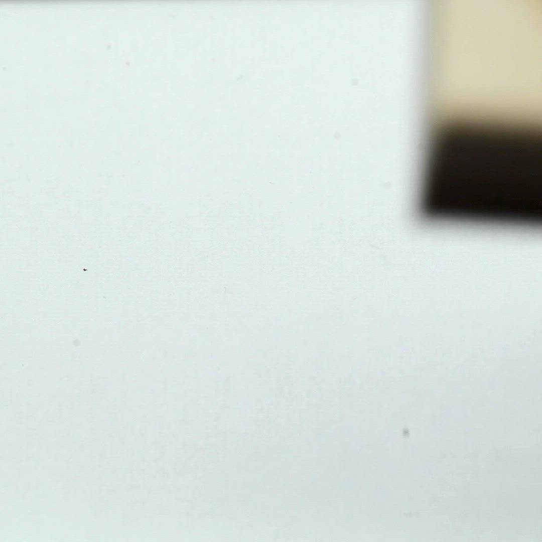 A closeup video of a man stamping on white paper, leaving the line art of a human brain. The folds of brain matter form the hidden image of a sleeping cat.