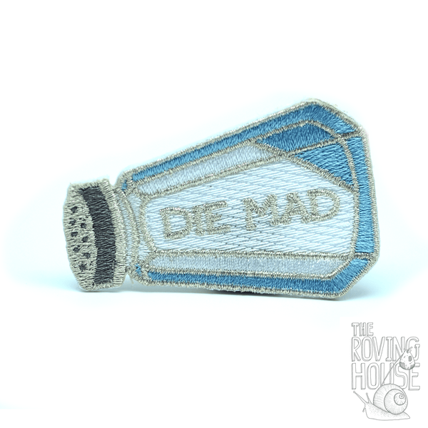 An embroidered patch in the shape of a classic blue and silver salt shaker, featuring white glitter "salt" and text that reads "DIE MAD".