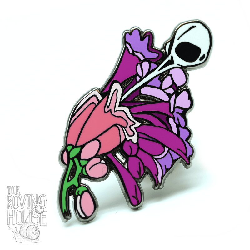 A hard enamel pin of a hummingbird skull sipping from some blossoms.