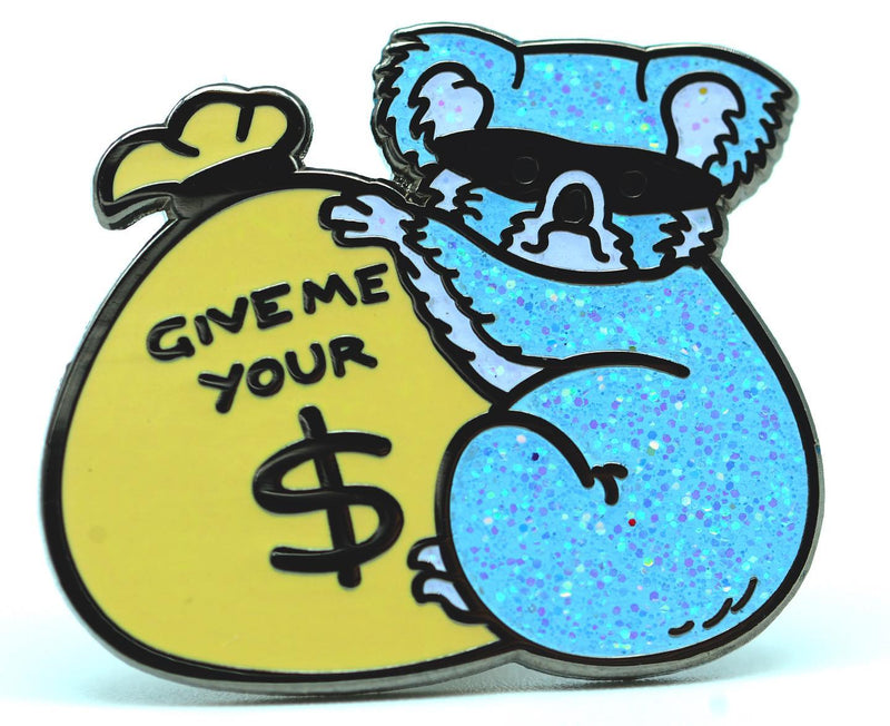 Enamel pin of a glittery koala bear wearing a robber mask and holding a sack of cash that says "GIVE ME YOUR $".