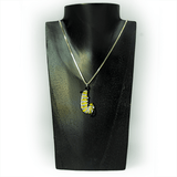 A monarch caterpillar enamel charm hanging from a silver box chain. The necklace sites on a black wooden display.
