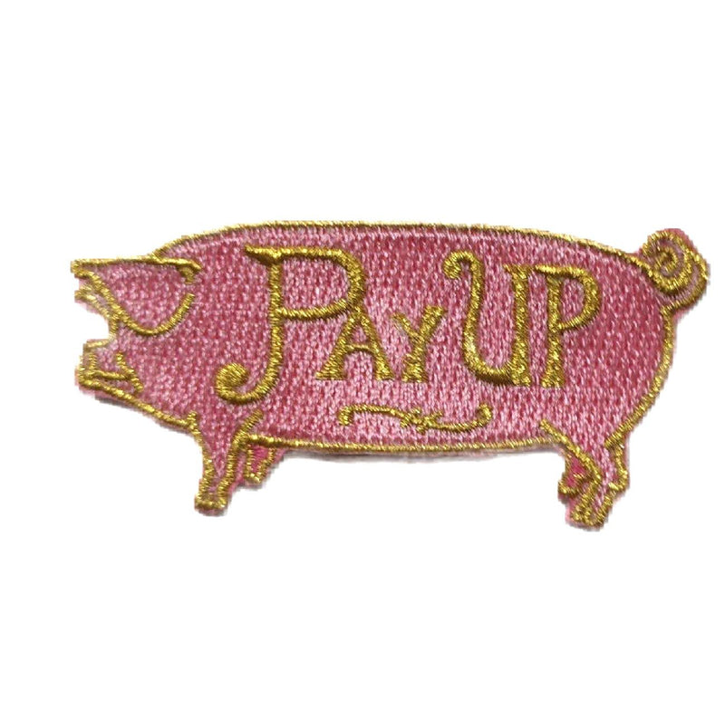 An embroidered patch resembling a pink pig, with the text "PAY UP" written in metallic gold on his side.