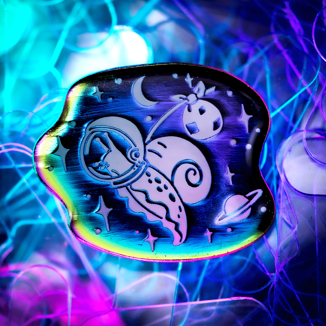The Roving House rainbow metal enamel pin, featuring an astronaut traveling snail and his bindle or hobo stick, floating in space